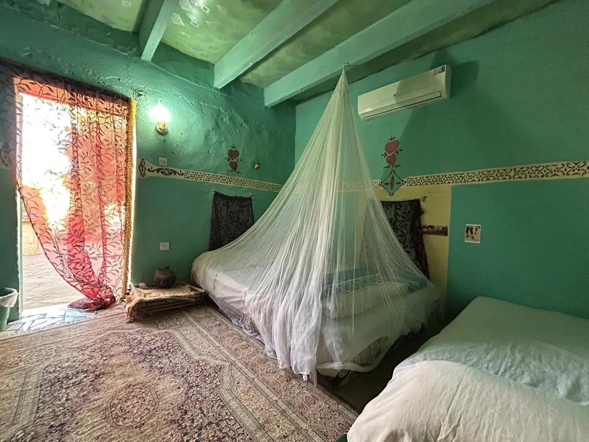 Chambre climatisée aux murs verts avec moustiquaire