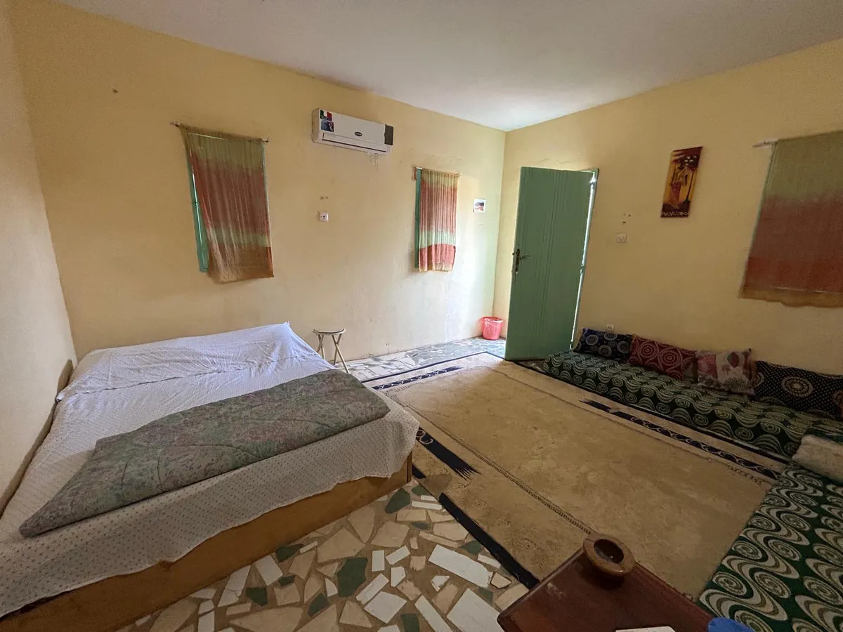 Chambre aux tons ocre avec lits et décoration locale